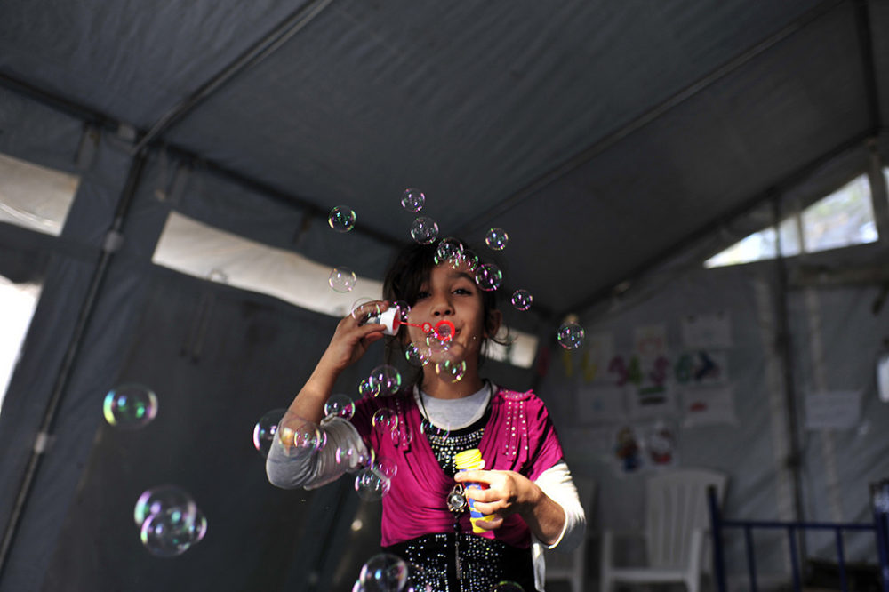 Mashable screen capture - refugee girl blowing bubbles in Serbia.