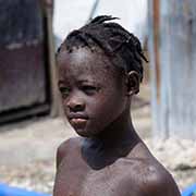 A girl with drops of water on her skin showers outside her makeshift home in a tent camp for people displaced by the Haiti earthquake.