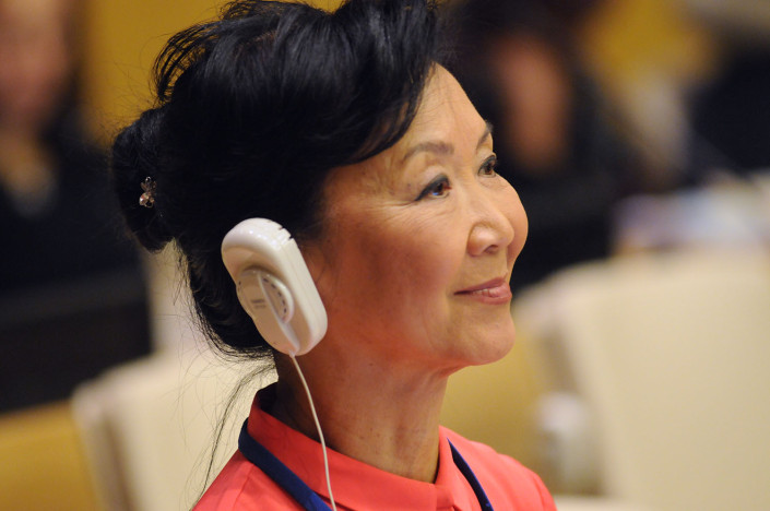 A woman wearing headphones listens at a meeting at the UN.