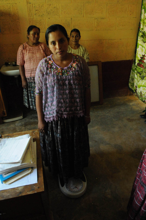 An indigenous Mayan woman, 7 months pregnant, is weighed at a health center in rural Guatemala.