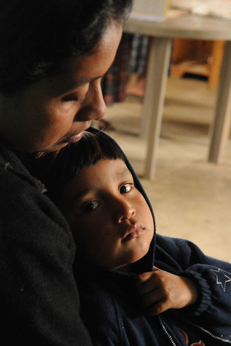 An indigenous Mayan woman holds her son at a rural health center while waiting for services, in rural Guatemala.