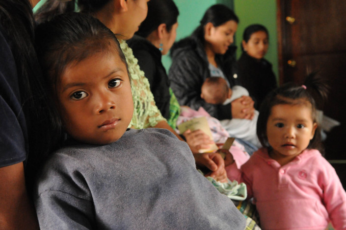 An indigenous Mayan girl waits with her mother and siblings, for a routine health checkup at a health center in rural Guatemala.