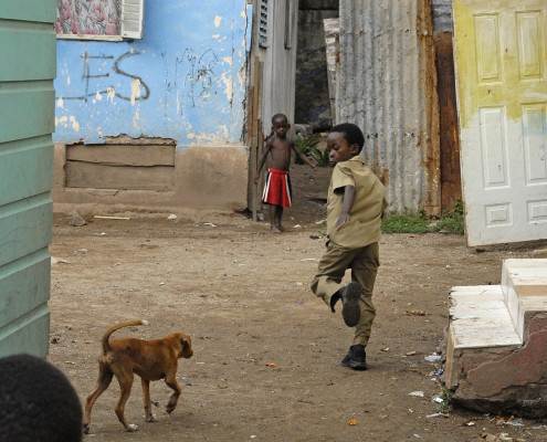 Children play outside their home as a dog walks nearby, in the community of Trenchtown in Kingston, Jamaica.