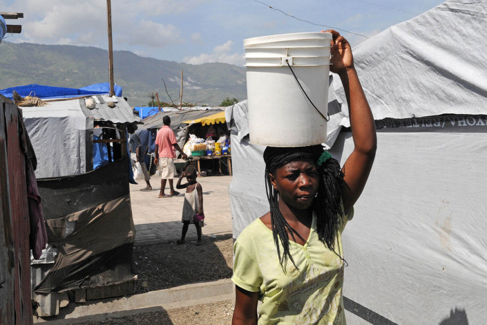 A woman carries a bucket of clean water on her head in Carrefour Aviation in Port-au-Prince, Haiti.