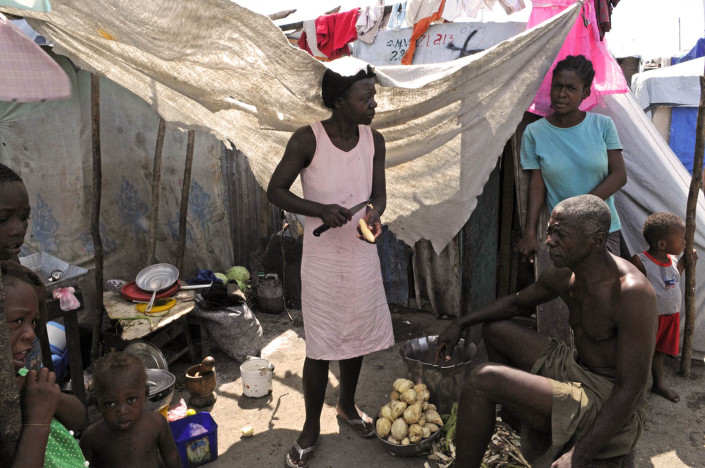 A family prepares a midday meal in their makeshift home at Carrefour Aviation, a tent camp housing 50,000 people who were displaced by the quake.By late June 2010 in Haiti.