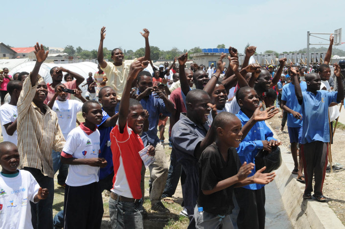A group of men and adolescent boys greet footballer Leo Messi, at Carrefour Aviation, Port-au-Price, Haiti.