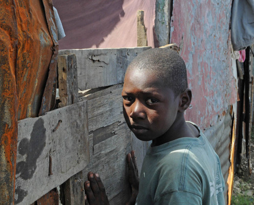 A boy leans against his makeshift home after the earthquake in Port-au-Prince, Haiti.