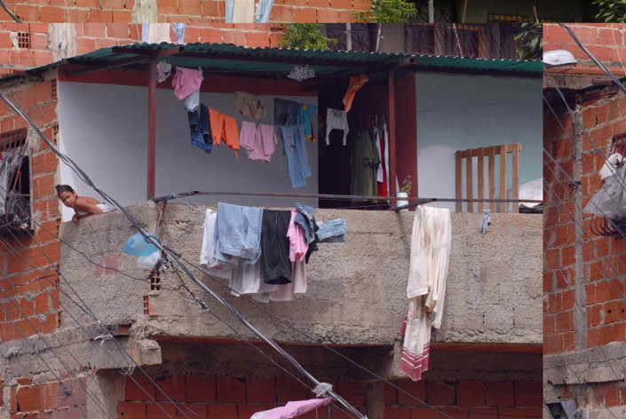 Laundry hangs from a balcony, as a girl leans over the side, in a poor neighborhood of Caracas, Venezuela.