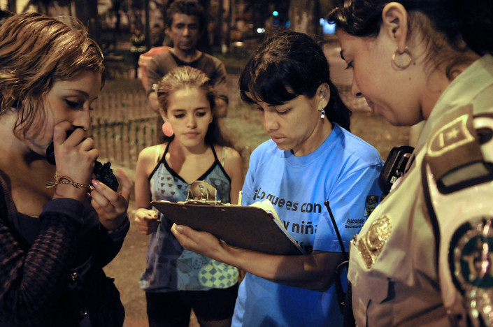 An outreach worker tries to convince a n adolescent girl on a street in Colombia to accompany her to a shelter.