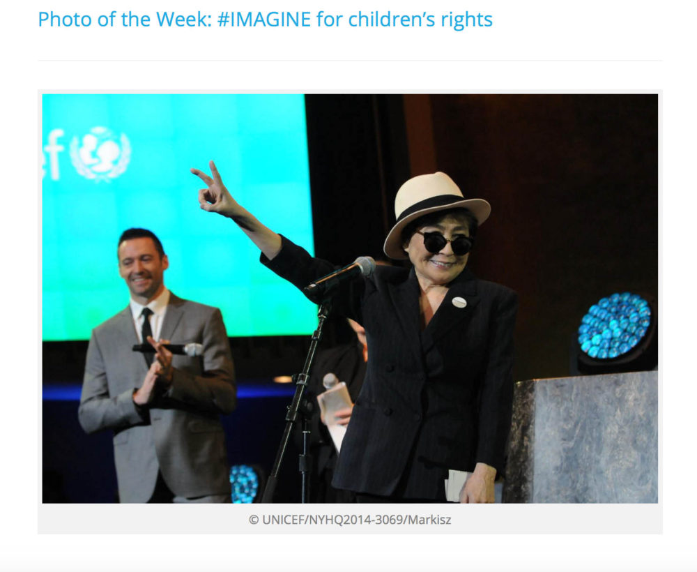 Yoko Ono gives the peace sign at the United Nations as actor Hugh Jackman stands behind her.