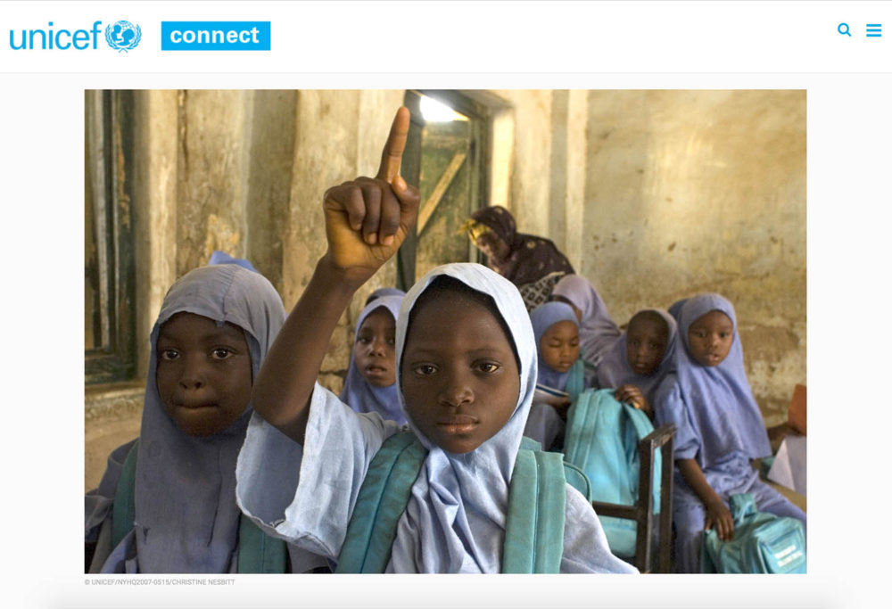 Screen capture showing a photograph of Nigerian schoolgirls, one raising her hand in the foreground.