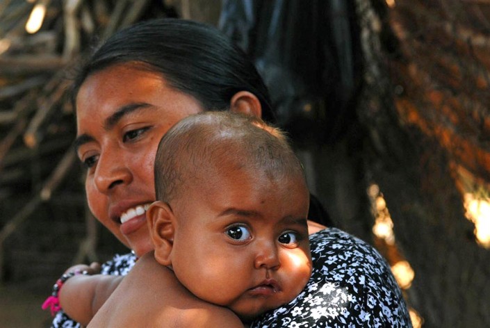 An indigenous Wayuu mom, Celina, holds her wide-eyed infant daughter Yenyiruska in the backyard of their home in Maracaibo, Venezuela.
