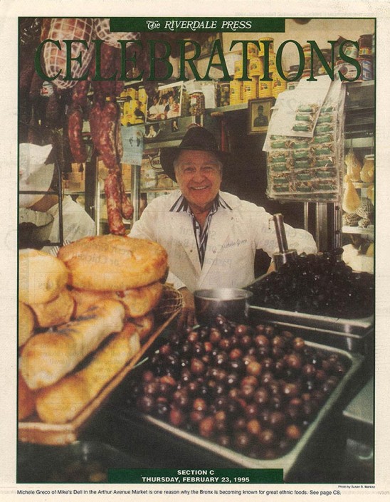 Tear sheet of Michele Greco, owner of Mike's Deli in the Bronx, standing behind his counter filled with freshly made bread, olives and sausages.