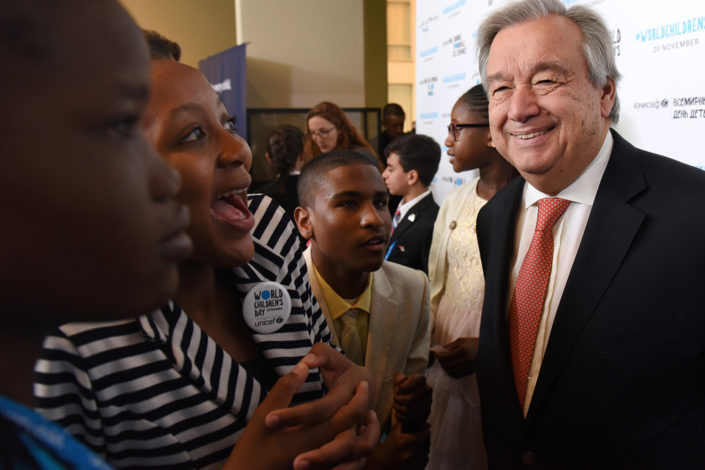UN Secretary-General António Guterres speaks with smiling adolescent activists at the UN.