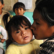 A woman tenderly kisses her infant daughter at a health center in Guatemala.