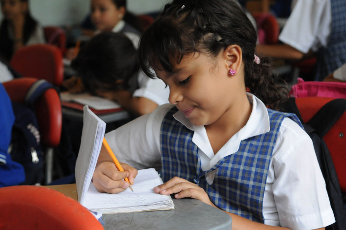 A 7-year-old girl writes in her Spanish notebook in a classroom in Medellín, Colombia.