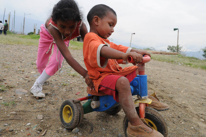 A girl pushes a boy near their homes on a toxic landfill known as El Morro in Medellin, Colombia.