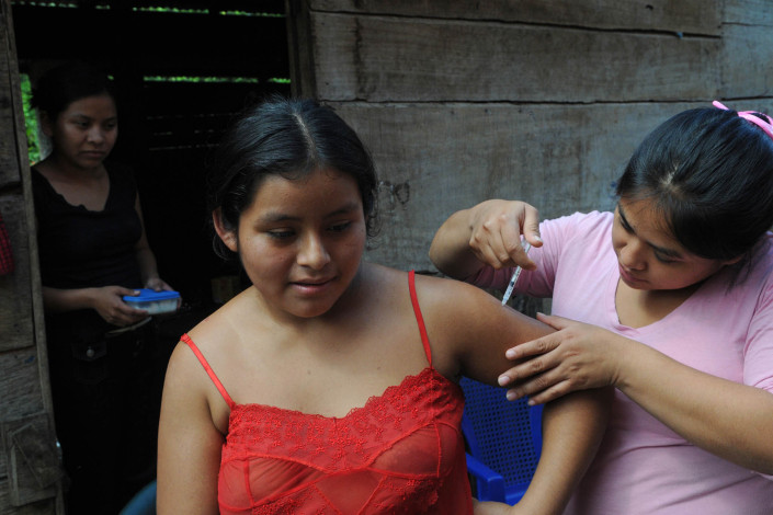 A health worker administers a tetanus vaccine to an indigenous Mayan woman outside her home in rural Guatemala.
