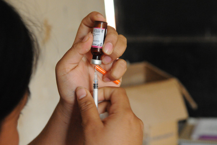 A health worker fills a syringe with measles vaccine at a rural health center in Guatemala.