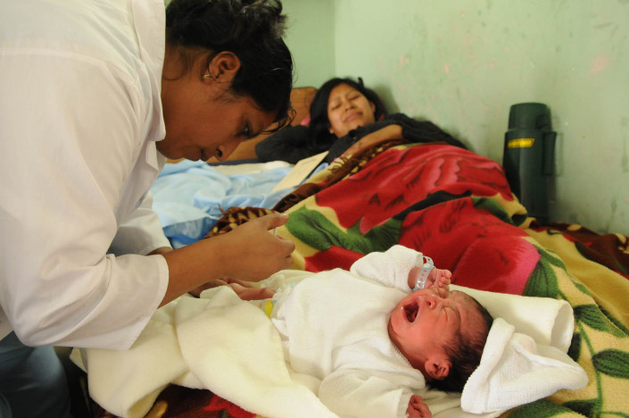 A mother winces as a newborn baby cries as a nurse administers a tuberculosis vaccination at a hospital in Guatemala.