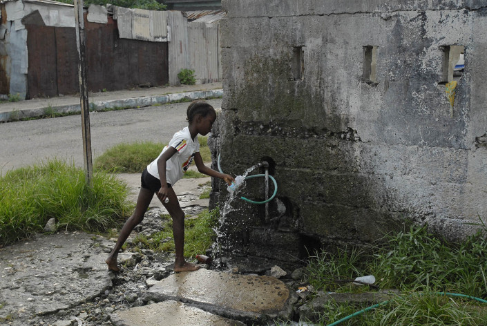 A girl fills a plastic bottle with drinking water at a local water point in Trenchtown in the parish of Kingston and St. Andrew, Jamaica.