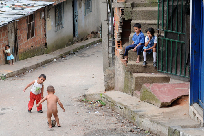 Small children play football as others watch nearby, in a poor neighborhood in Medellin, Colombia.
