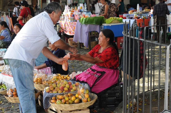A woman sells fruit at a market to a man in Antigua, Guatemala.