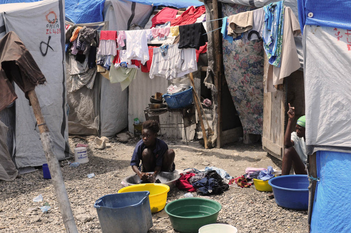 A woman washes clothing outside her makeshift home at Carrefour Aviation, a tent-camp, in Port-au-Prince, Haiti, after the June earthquake that killed more than 225,00 and displaced more than two million people.