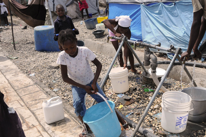 A girl collects water from a pump in Carrefour Aviation, a tent camp housing 50,000 people who were displaced by the earthquake in Haiti,