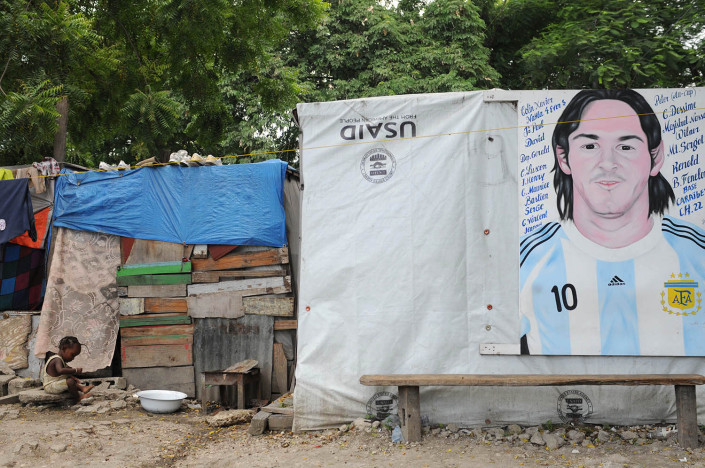 A child plays outside a makeshift tent bearing a portrait of Argentinean football player Lionel Messi, in Port-au-Prince, Haiti.