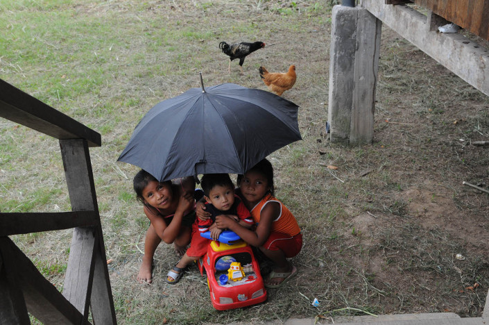 Children play with a plastic toy car under an umbrella outside their home in the indigenous Shipibo-Conibo community of Nuevo Saposoa in the Peruvian Amazon.