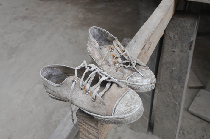 A pair of well-worn sneakers sit on a wooden beam of a wooden house in the indigenous Shipibo-Conibo community of Nuevo Saposoa in the Peruvian Amazon.