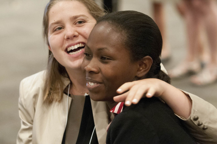 Two young women embrace at a disabilities conference.