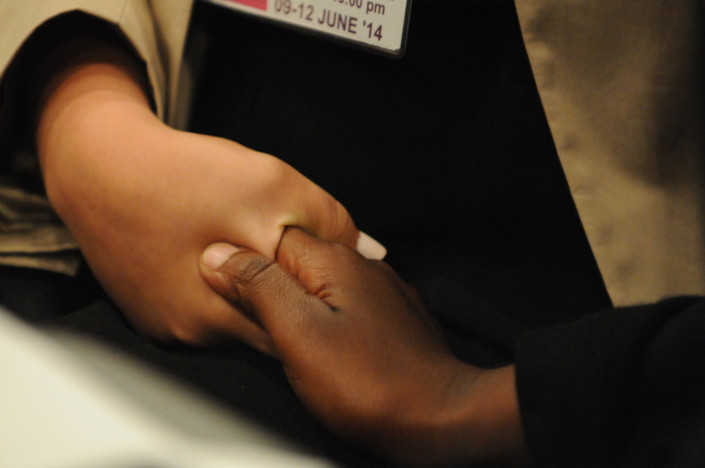 Two young women hold hands at a disabilities conference.
