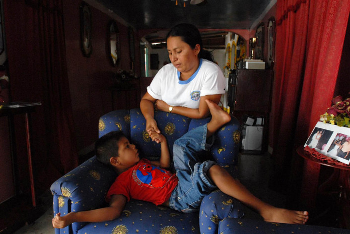 A 5-year-old Añu boy holds his mother's hand, as he tells her a traditional story in their home in Laguna de Sinamaica, Venezuela.
