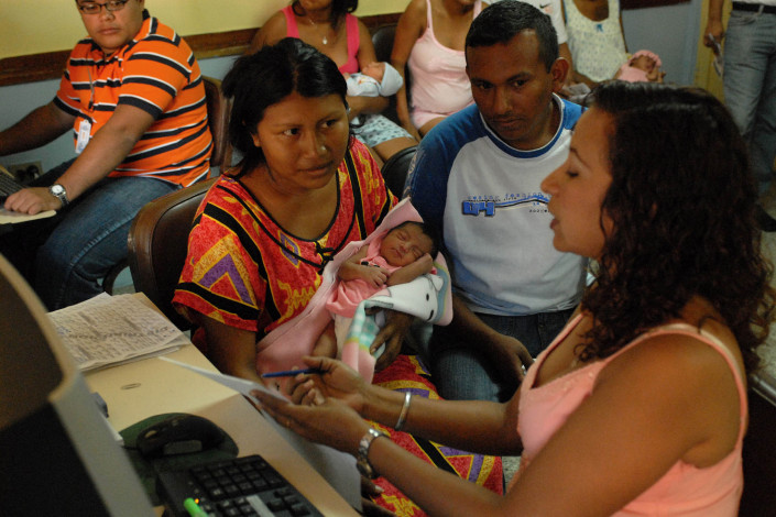 An indigenous Wayuu woman holds her newborn daughter as she and her husband obtain a civil birth registration certificate from a health worker in Maracaibo, Venezuela.