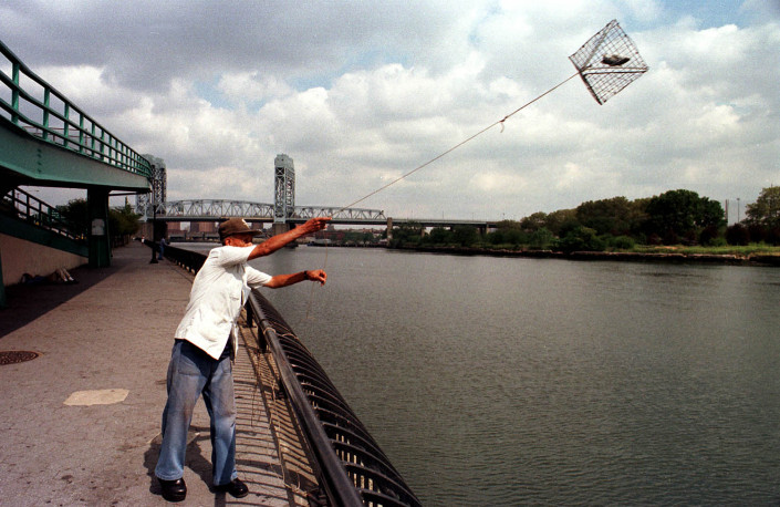 A man throws a crab trap with bait fish, into the East River in NYC.