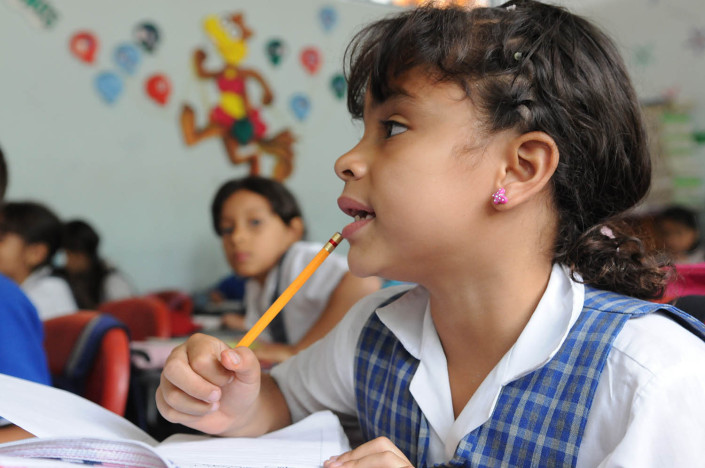 A girl holding a pencil, sits in a Spanish class in Medellín, Colombia.