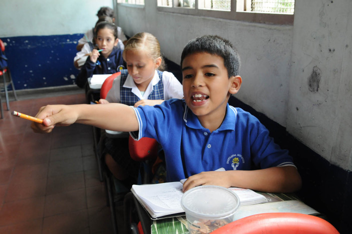 A boy raises his hand during a Spanish class in Medellín, Colombia.