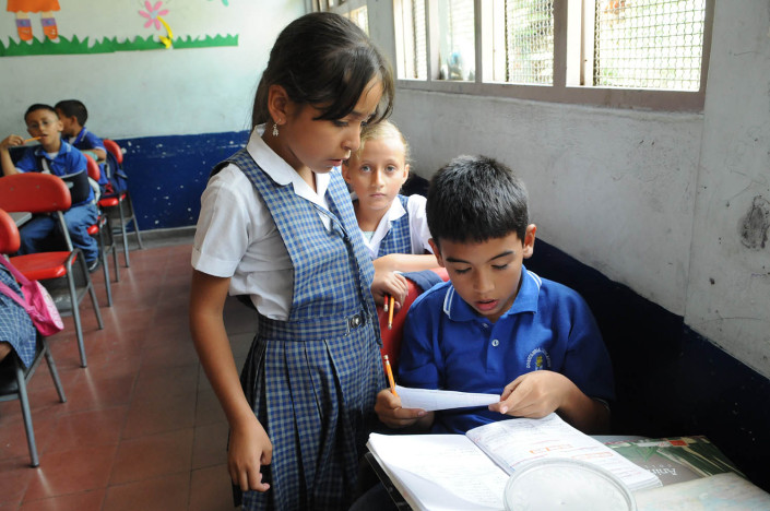 A girl helps a boy in Spanish class in Medellín