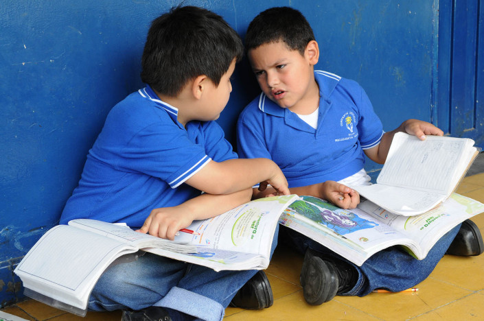 Boys sitting on the floor, discuss their schoolwork at a school in Medellín, Colombia.