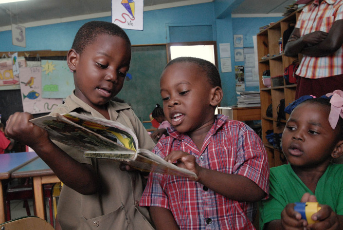 Boys read a book as a girl plays with colourful plastic blocks at a school in the parish of Kingston and St. Andrew, Jamaica.