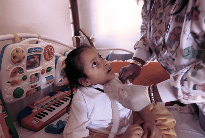 A nurse removes secretions from the ventilator of a boy with Spina Bifida.