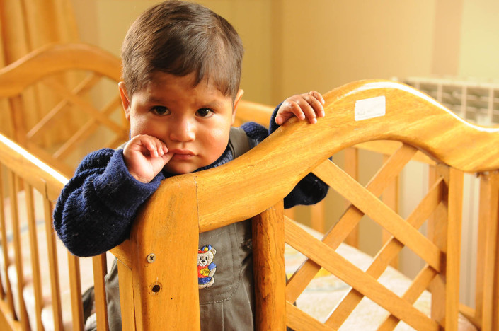 A toddler stands in a crib at a shelter in Potosí, Bolivia.