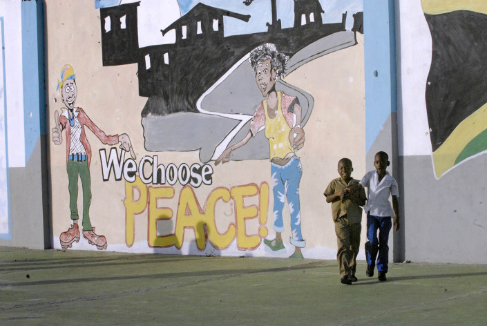 Children walk outside a painted mural that says "Peace Initiative."
