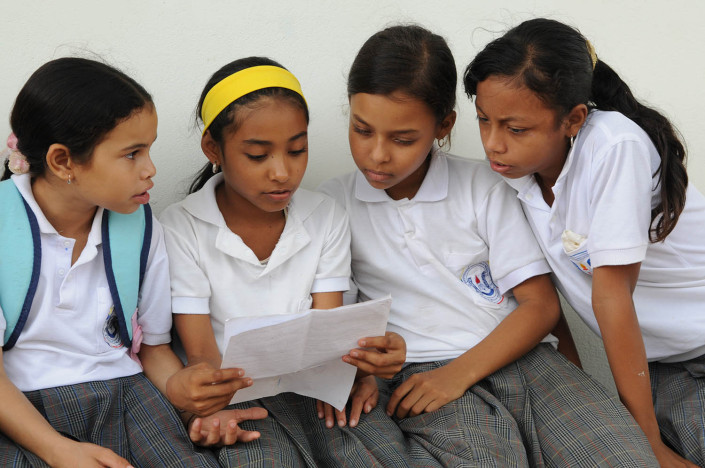 Girls discuss work together outside their classroom in Lorica, Colombia.