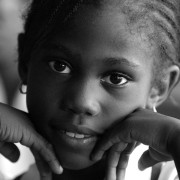 A wide-eyed schoolgirl leans on her hands during a classroom discussion in Jamaica.