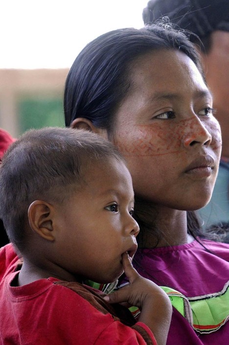 A woman wearing traditional Shipibo costume and paint on her face, stands with her young son.