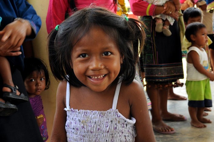 A smiling girl from the indigenous Shipibo-Conibo community of Nuevo Saposoa, stands with members of her community.