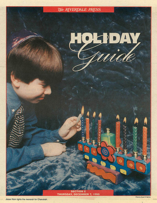 Jesse Klein lights the 7th candle on a colorful menorah.